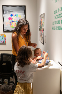 Photograph of a mom and two young children interacting with art at the museum